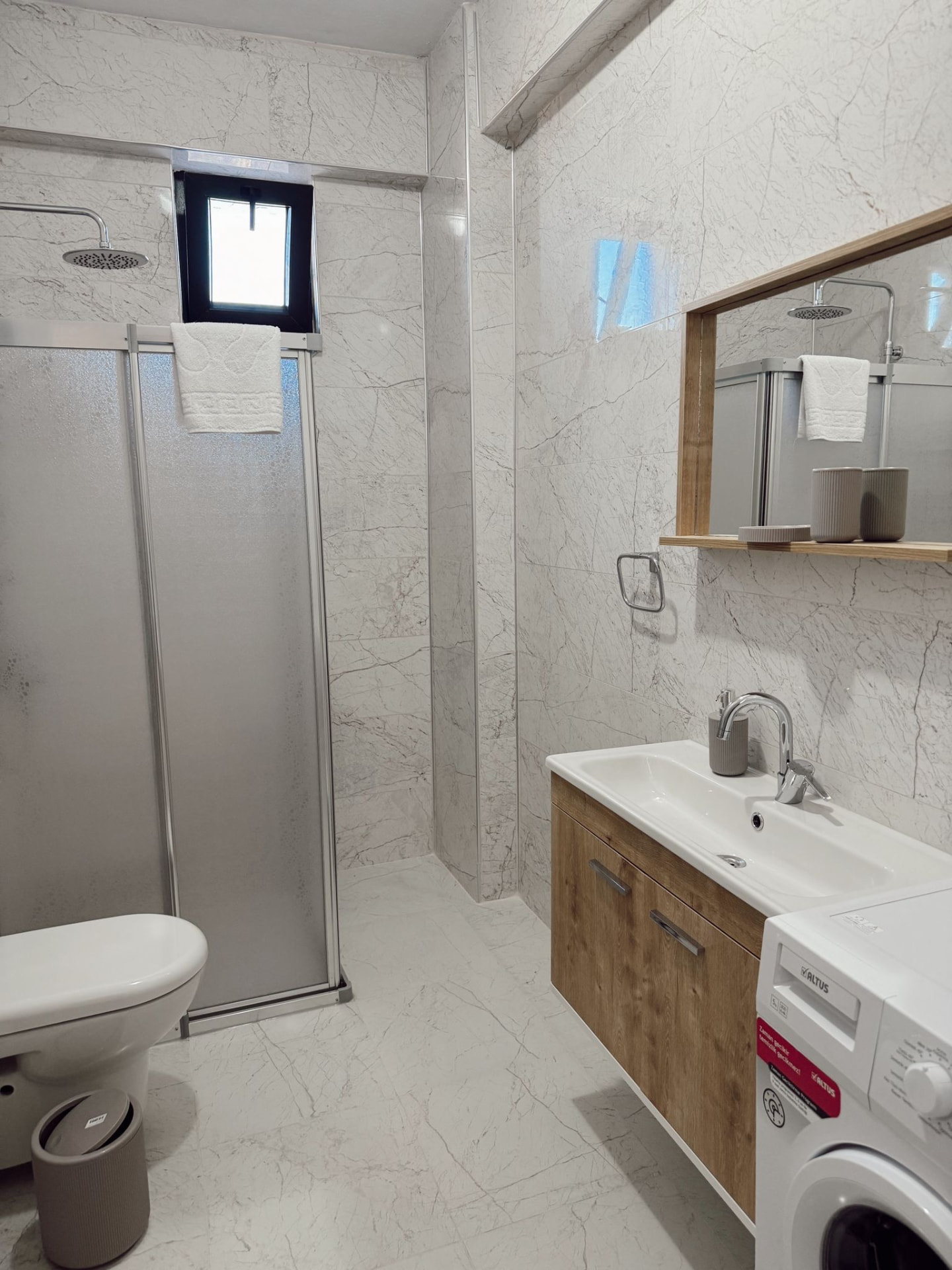 Suit banyosu, duşakabin ve ahşap dolaplı lavabo